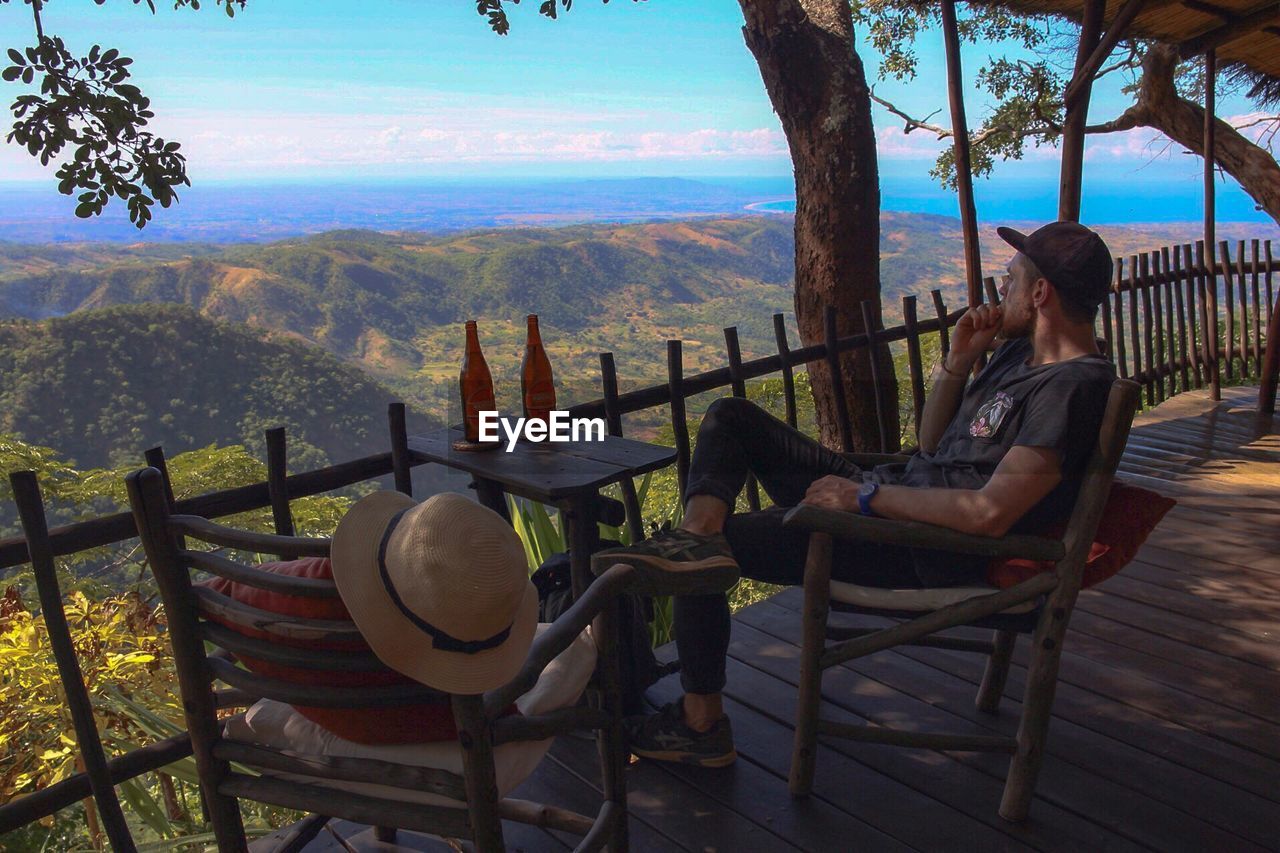 Man sitting on chair at observation point against mountain