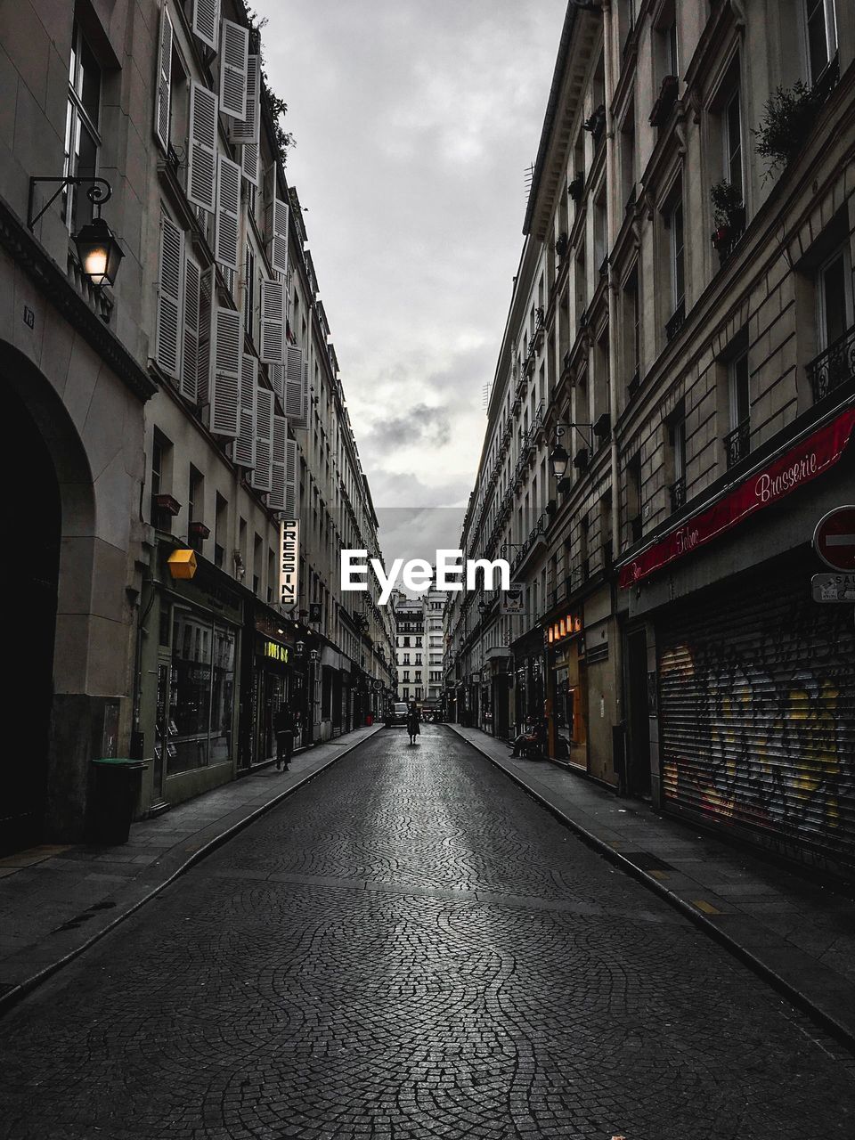 Empty road amidst buildings in city against sky