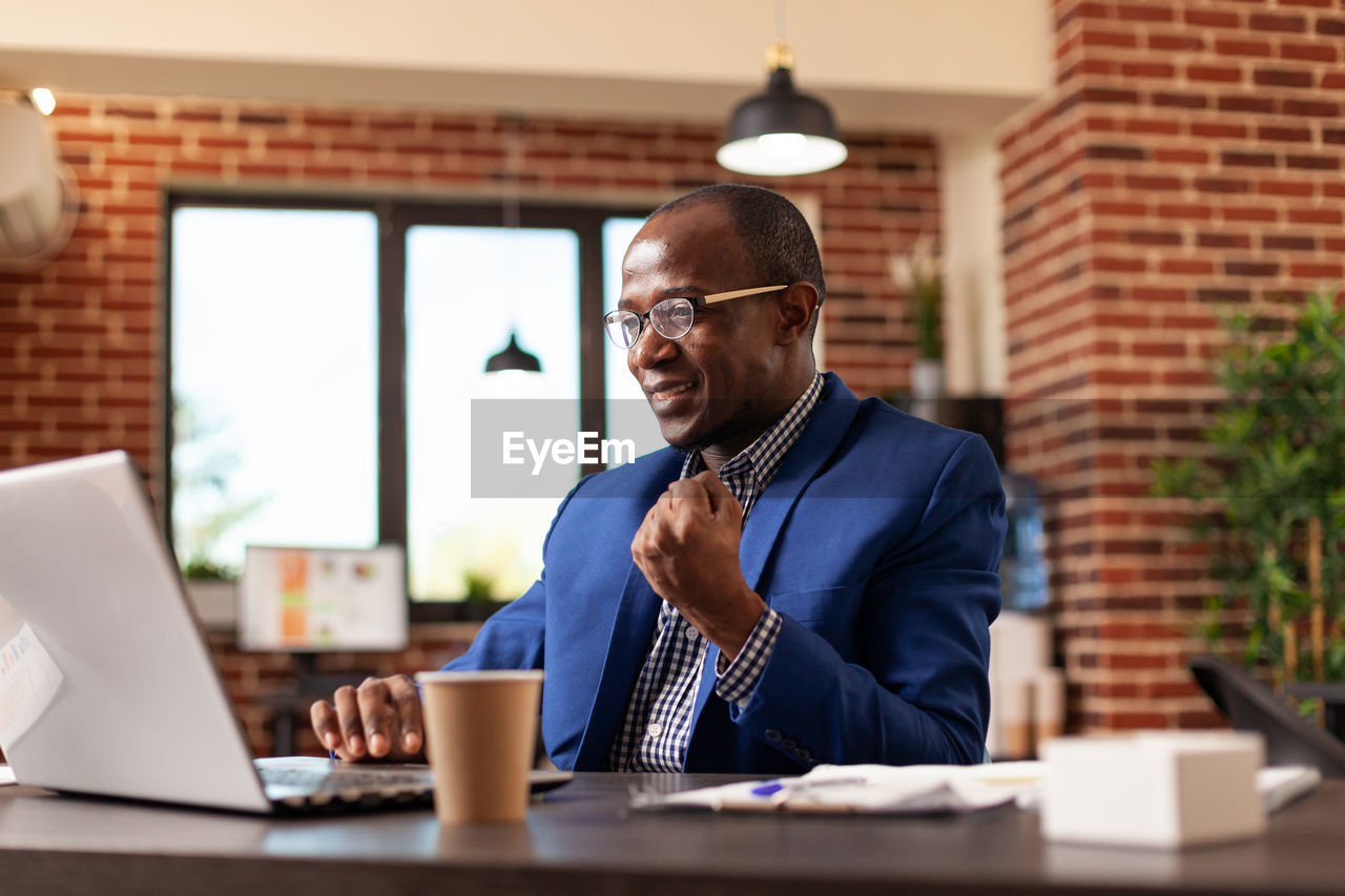 portrait of businessman using laptop while sitting in office