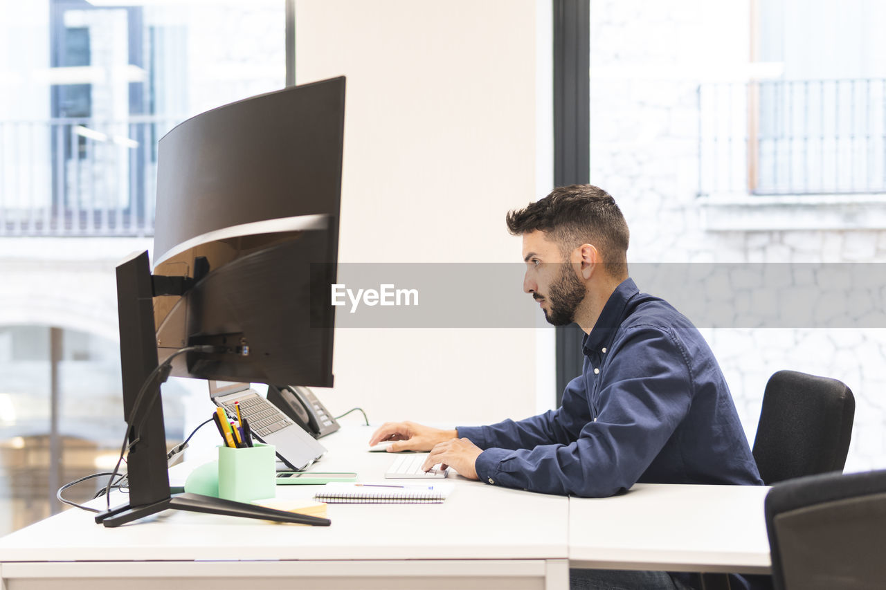 Young businessman working on laptop at desk in office