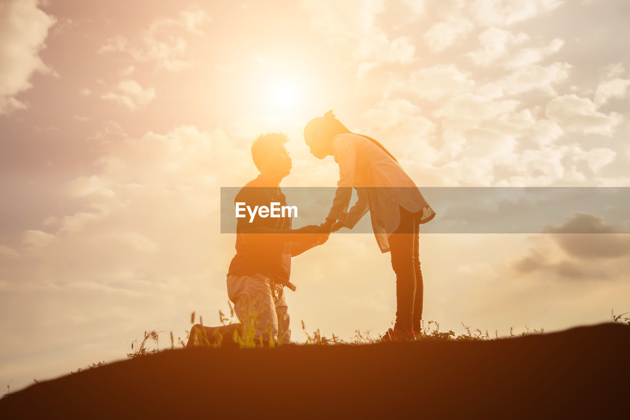 Low angle view of romantic silhouette couple on land against sky during sunset