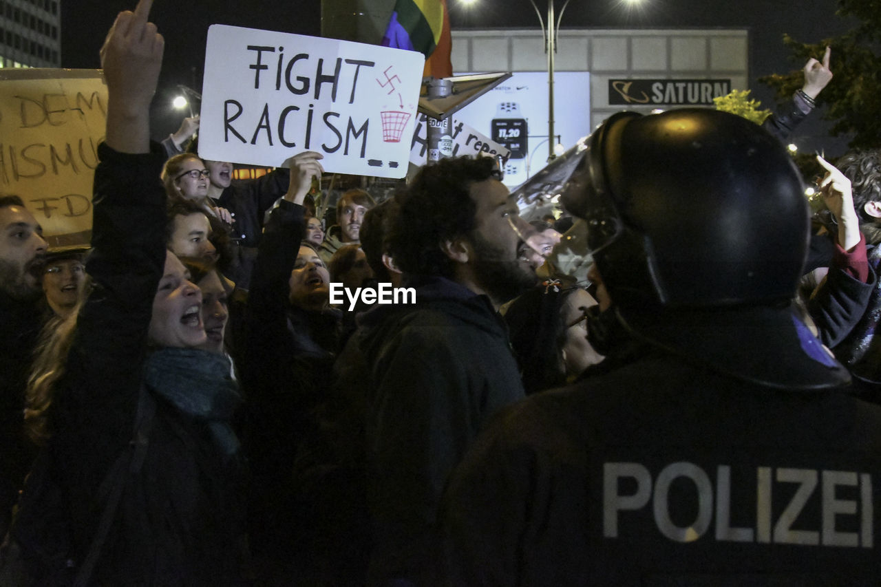 REAR VIEW OF PEOPLE ON STREET IN CITY AT NIGHT