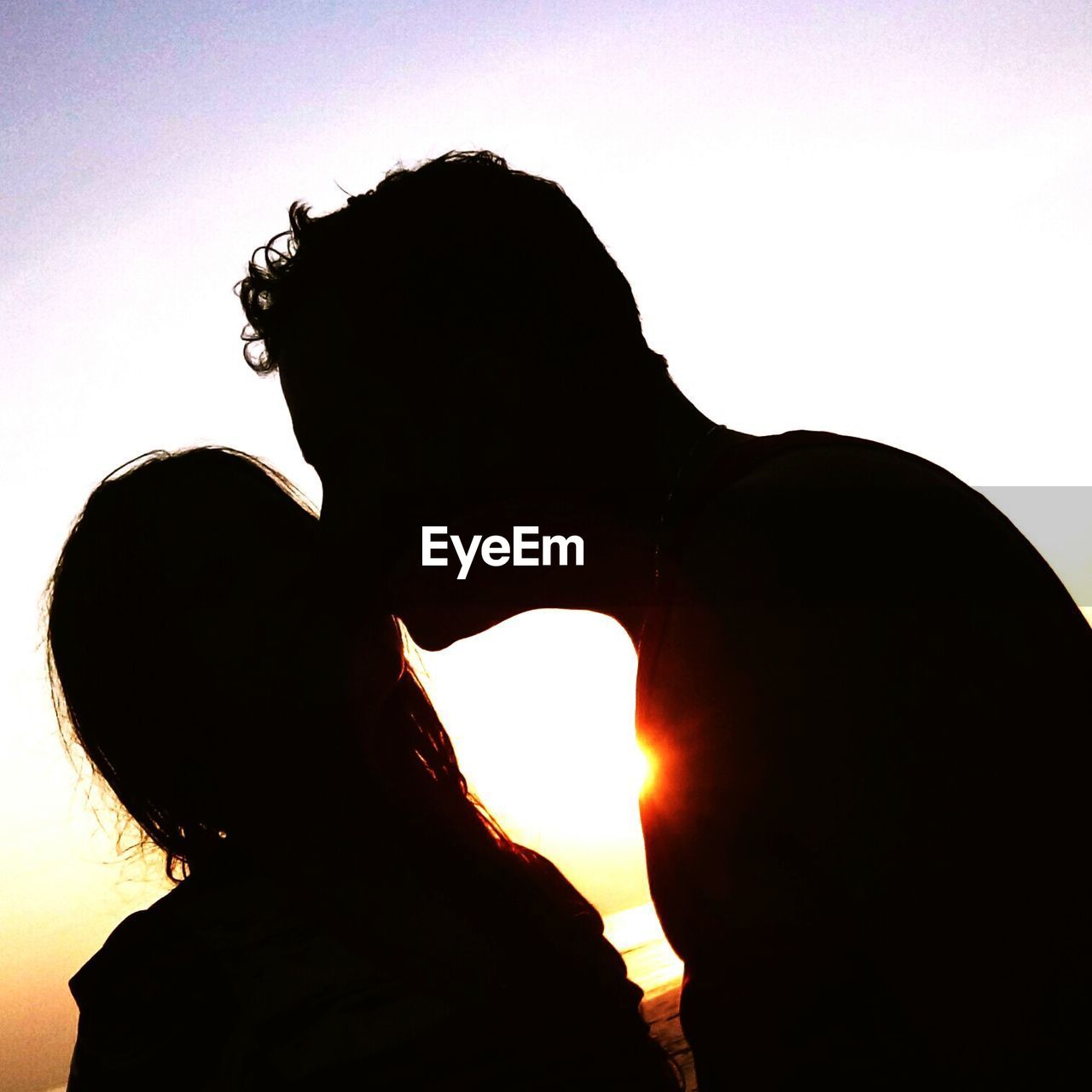 SILHOUETTE OF COUPLE AGAINST SKY DURING SUNSET