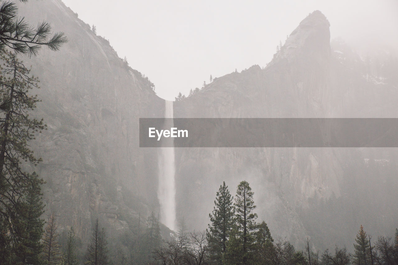 Scenic view of waterfall in forest against sky