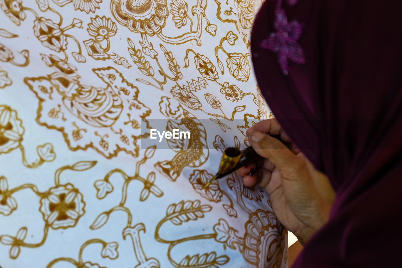 Close-up of woman making design on fabric
