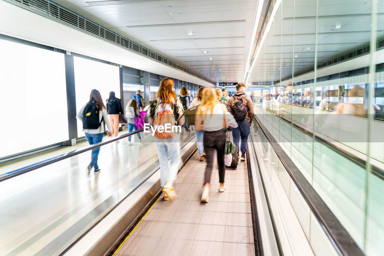 REAR VIEW OF PEOPLE WALKING ON ESCALATOR IN SUBWAY