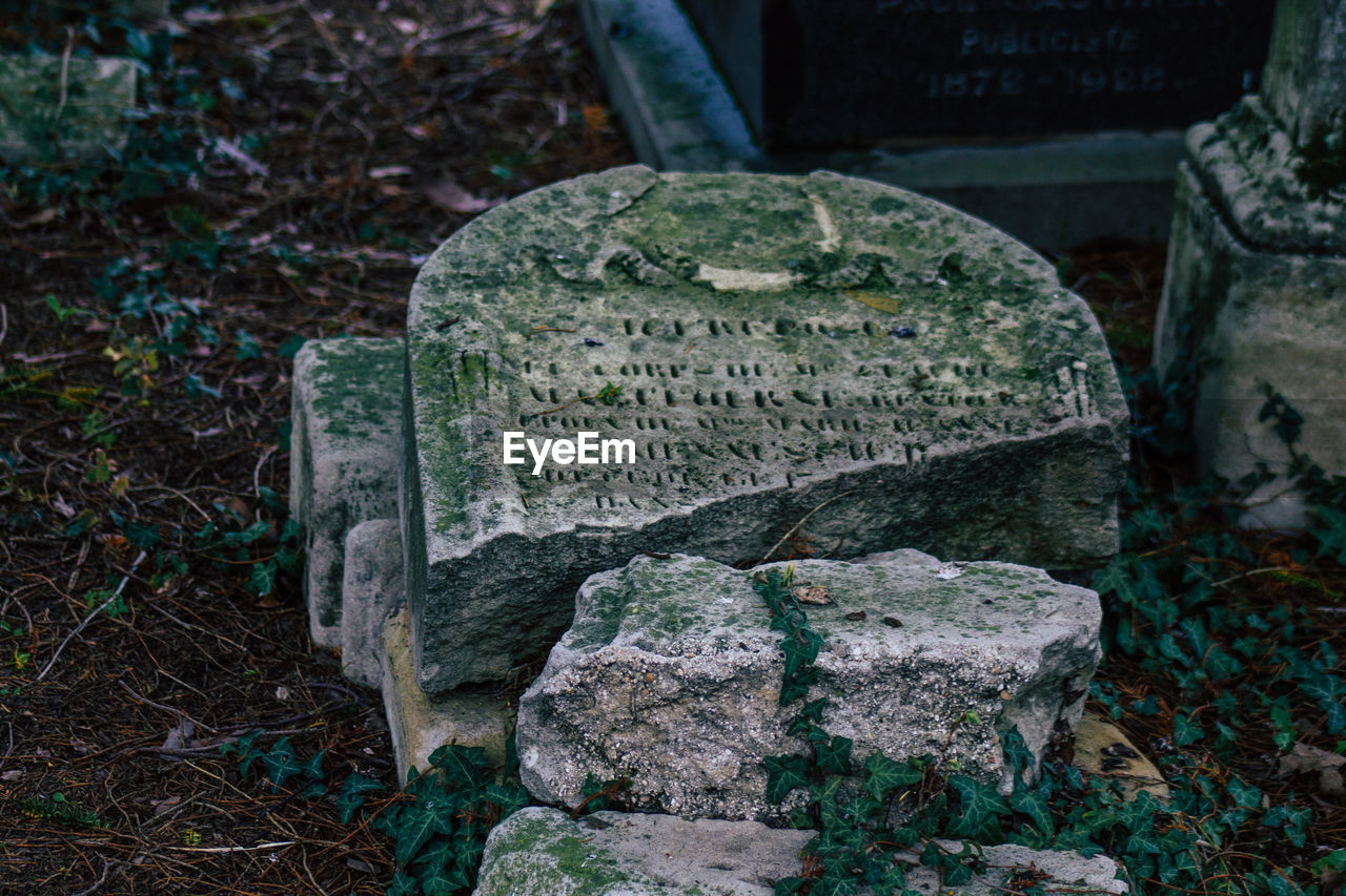 CLOSE-UP OF STONE CROSS ON CEMETERY