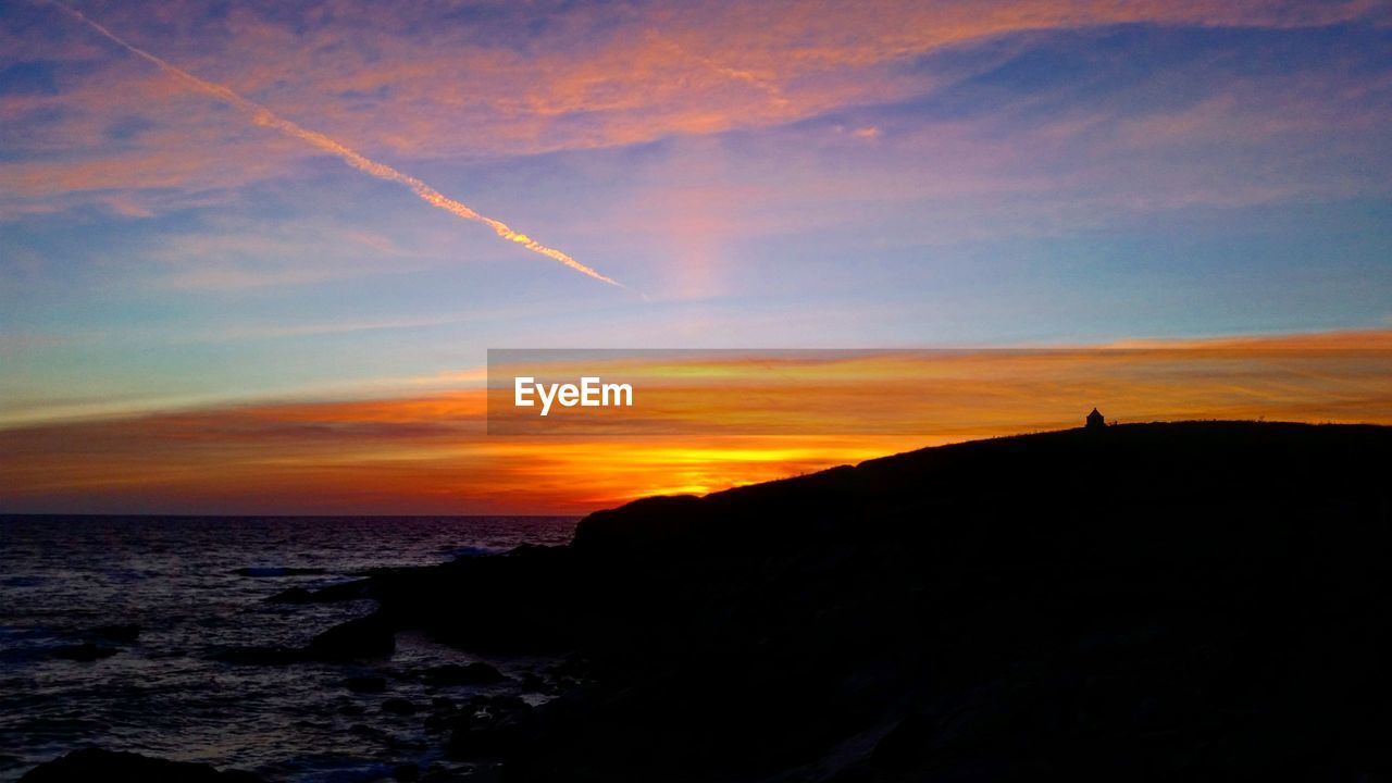 SCENIC VIEW OF SILHOUETTE BEACH AGAINST SKY DURING SUNSET