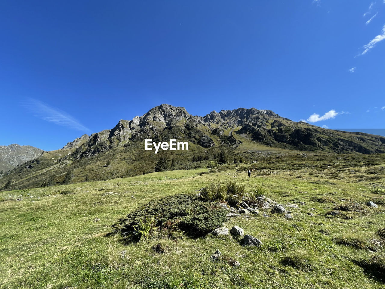 Scenic view of land and mountains against blue sky