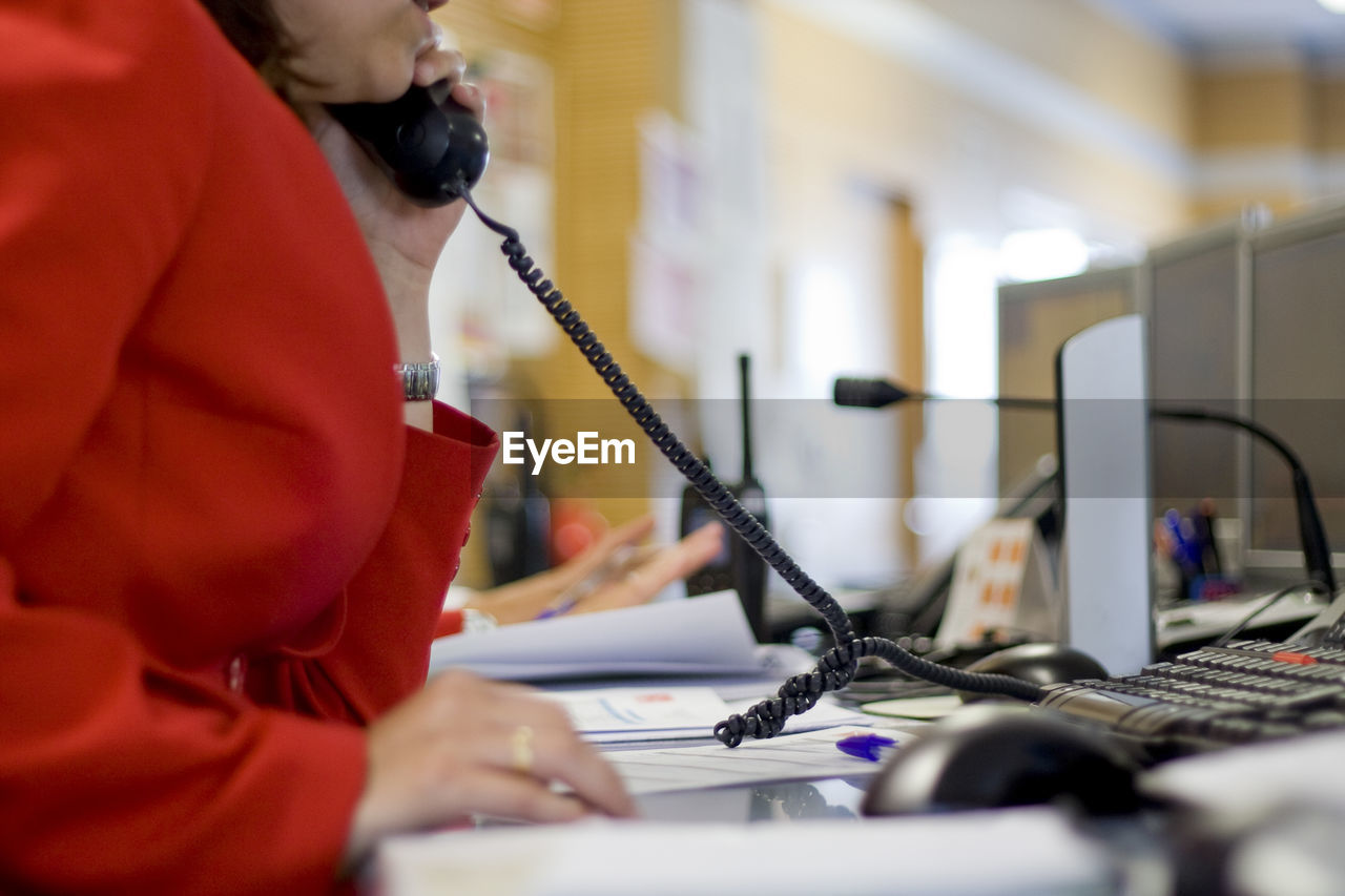 Midsection of woman talking over phone in office