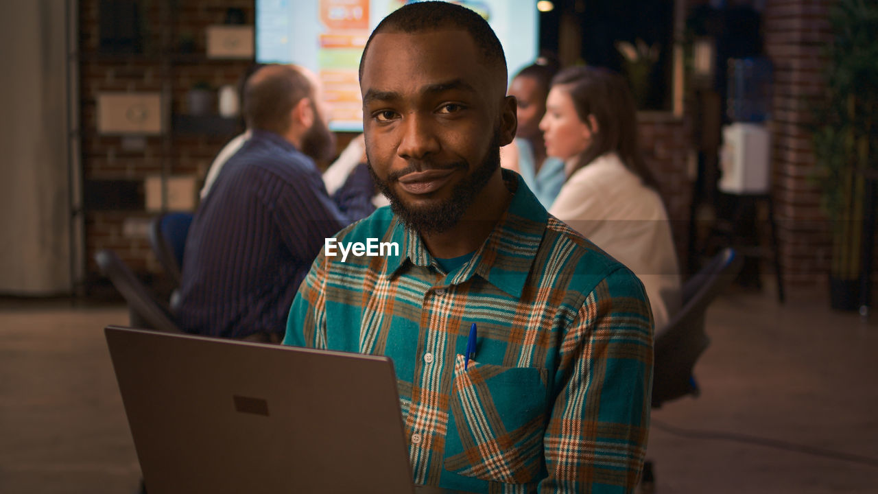 portrait of man using laptop while sitting at cafe