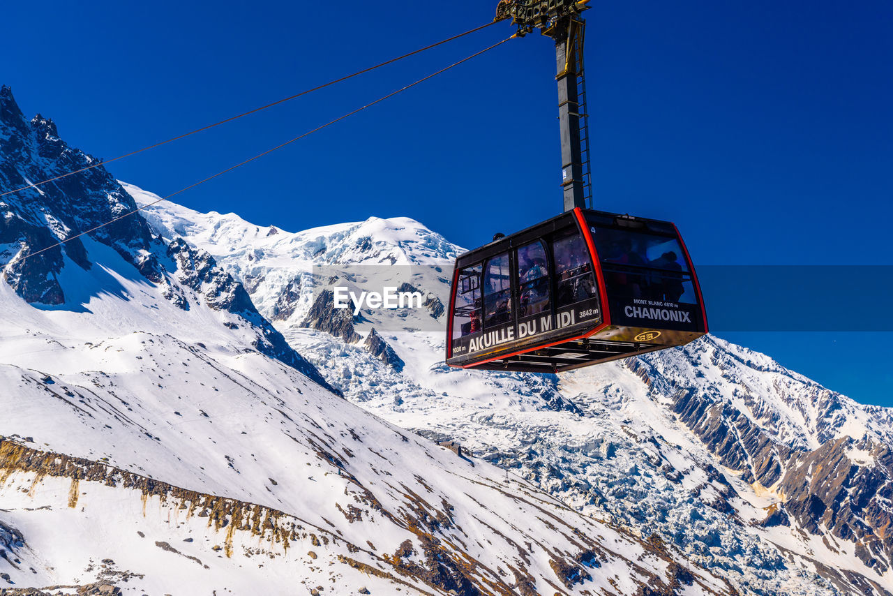 LOW ANGLE VIEW OF SKI LIFT AGAINST SNOWCAPPED MOUNTAINS