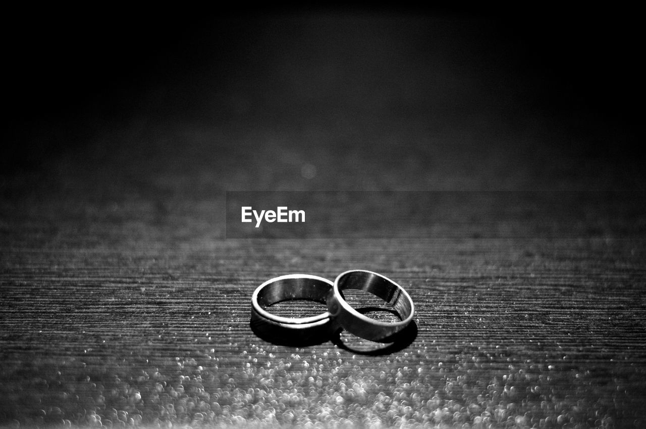 CLOSE-UP OF WEDDING RINGS ON TABLE WITH EYEGLASSES