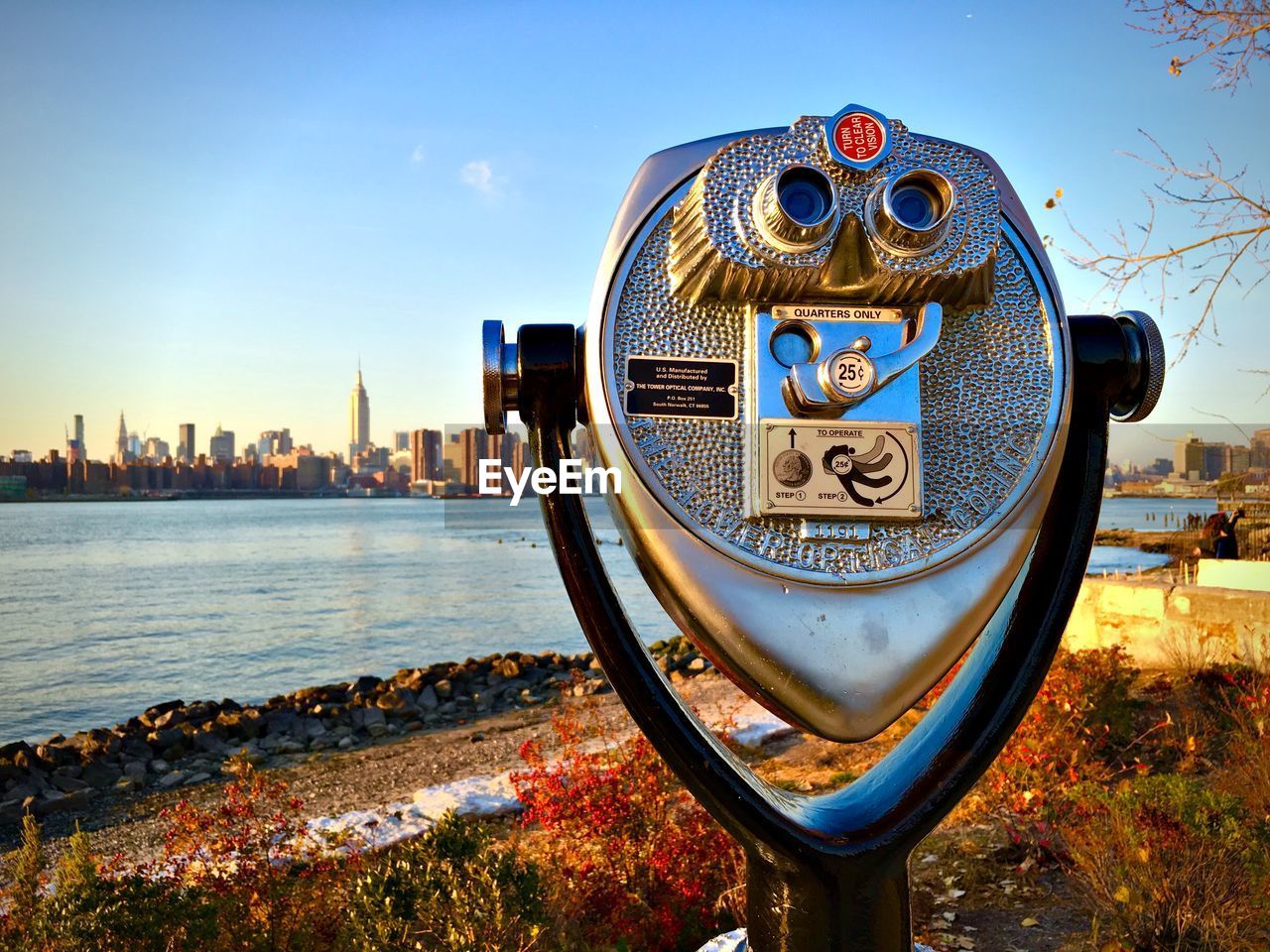 Close-up of coin-operated binoculars by river against sky