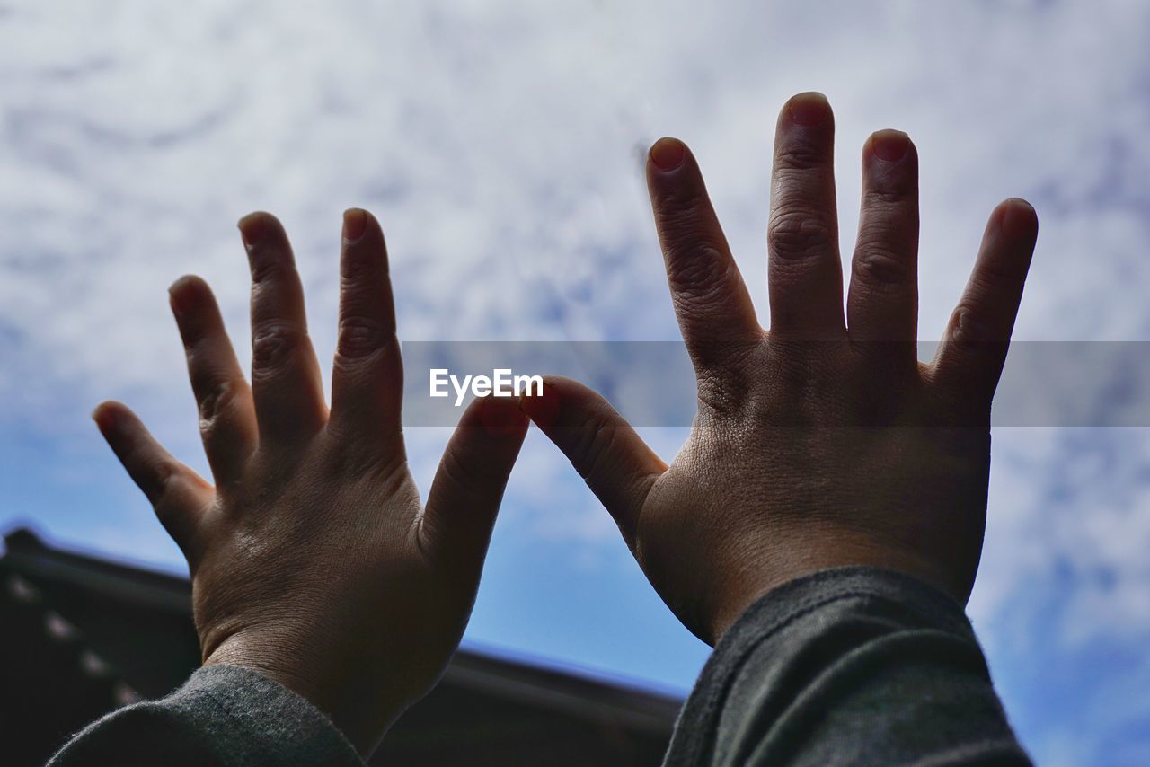 Cropped hands of person on glass window