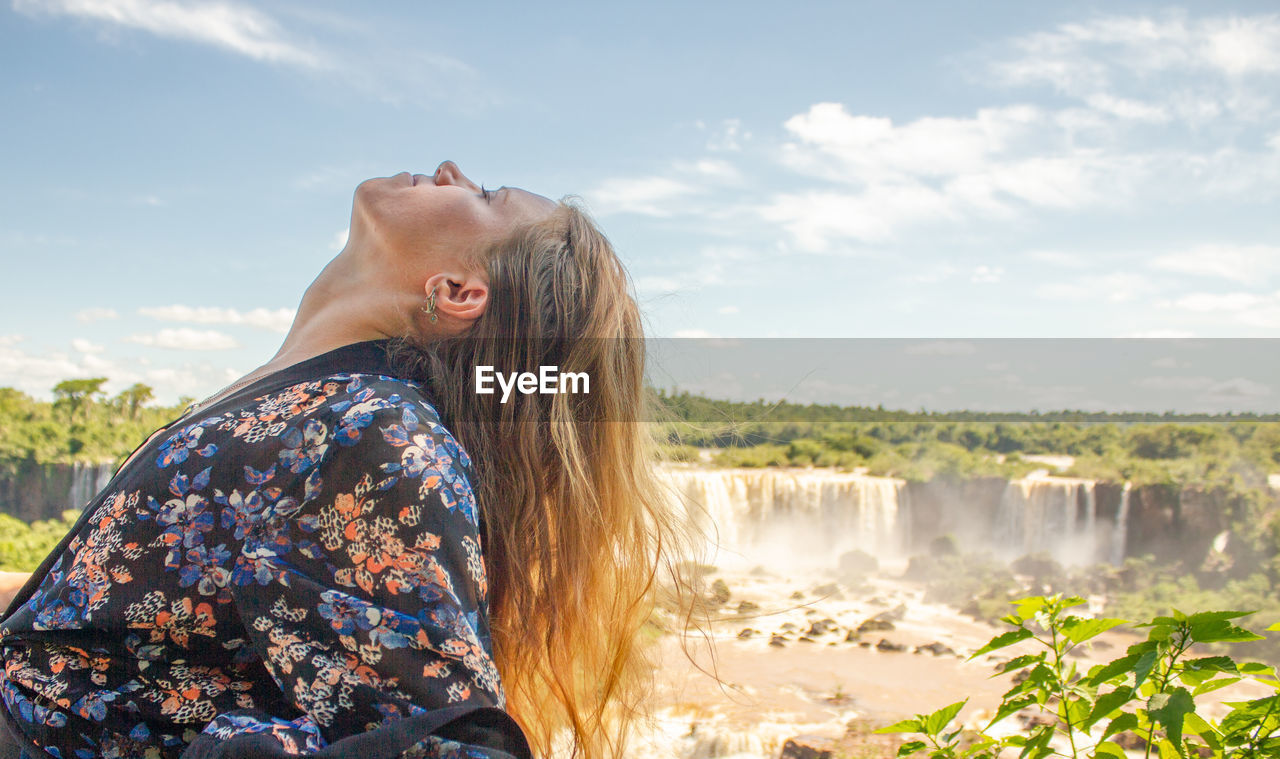 Side view of woman looking at waterfall