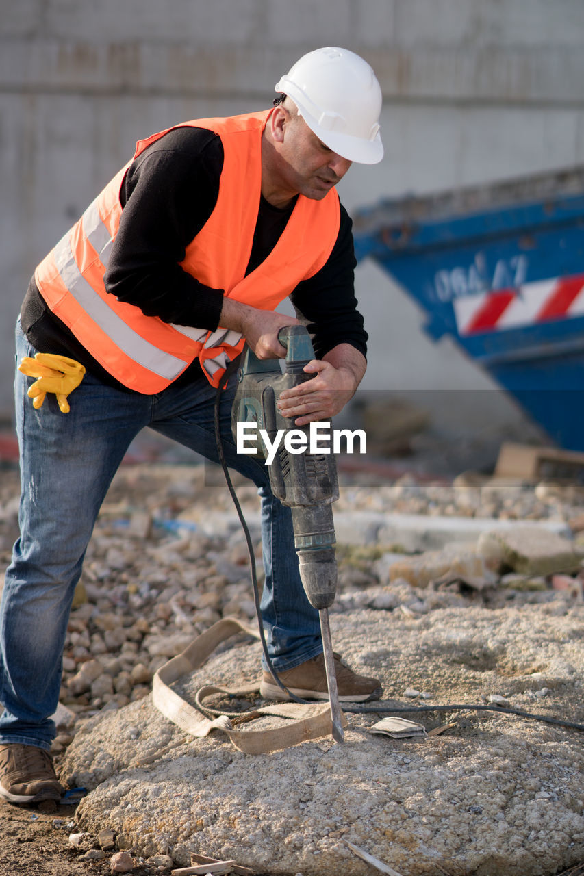 Worker drilling with jackhammer at construction site