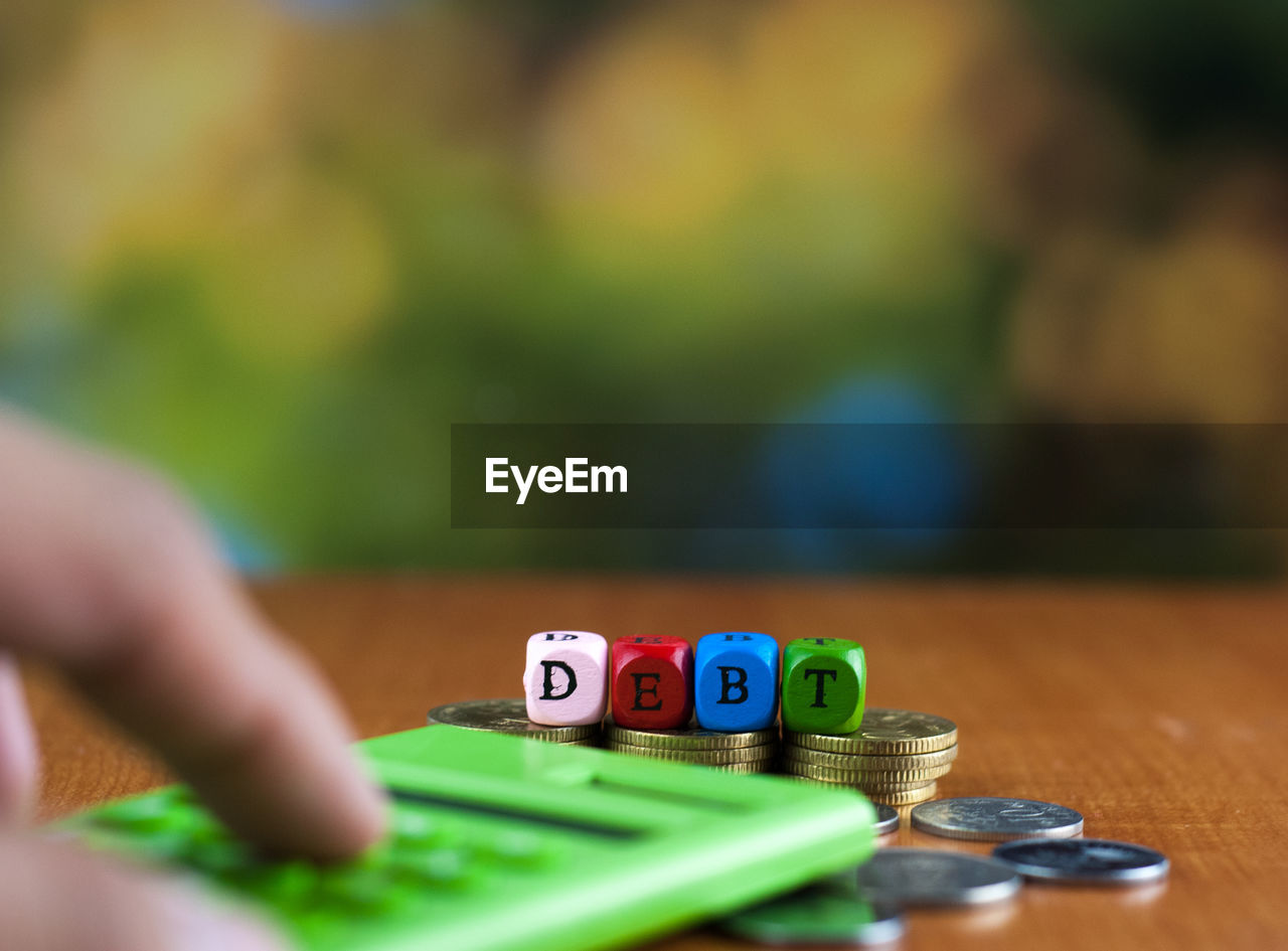 Close-up of person using calculator with coins on table