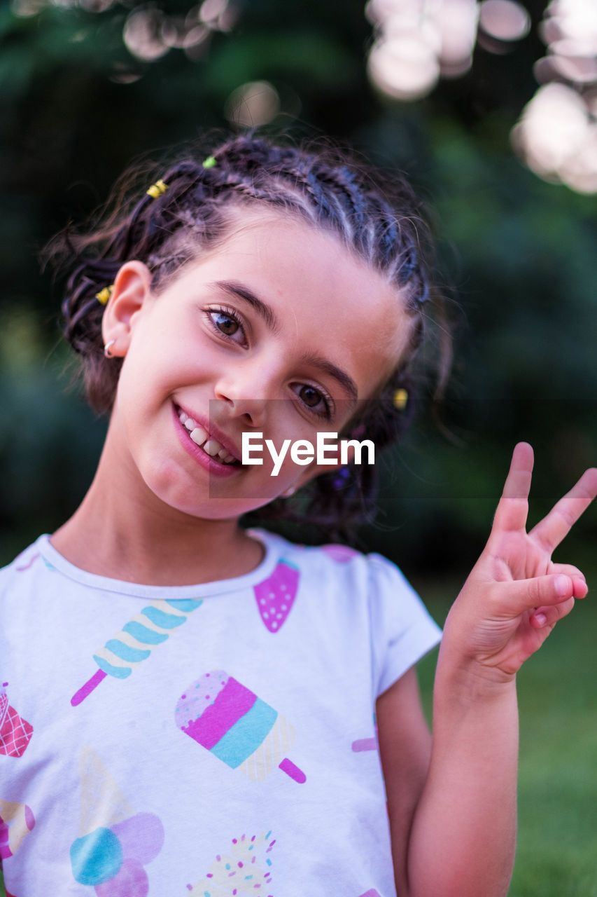 Portrait of smiling cute girl showing peace sign