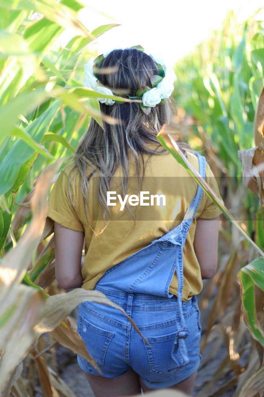 REAR VIEW OF WOMAN STANDING AMIDST PLANTS