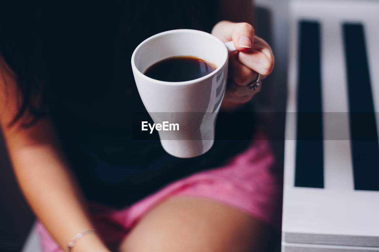 Midsection of woman holding coffee cup