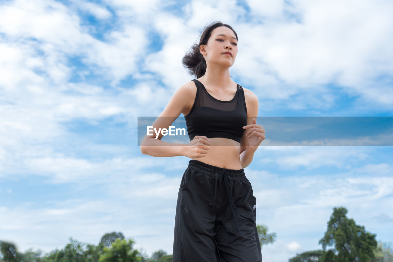 Low angle view of woman exercising against sky