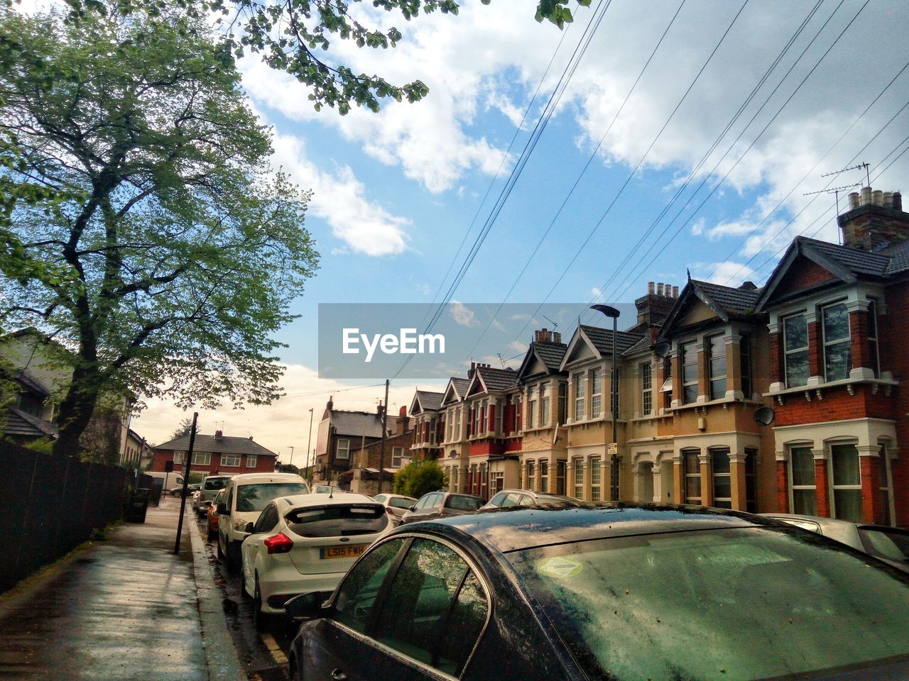 CARS ON ROAD AMIDST BUILDINGS AGAINST SKY