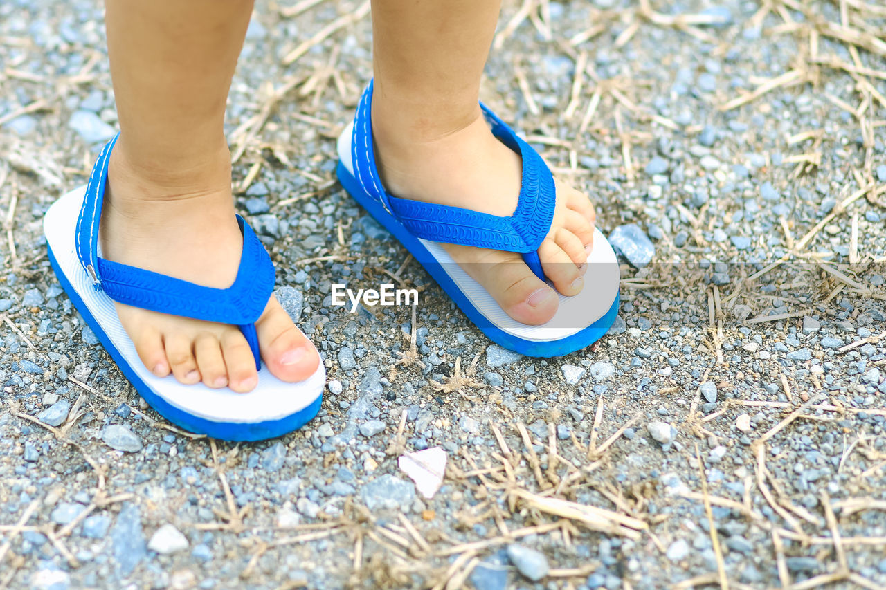 Child feet and sandals on pebble ground