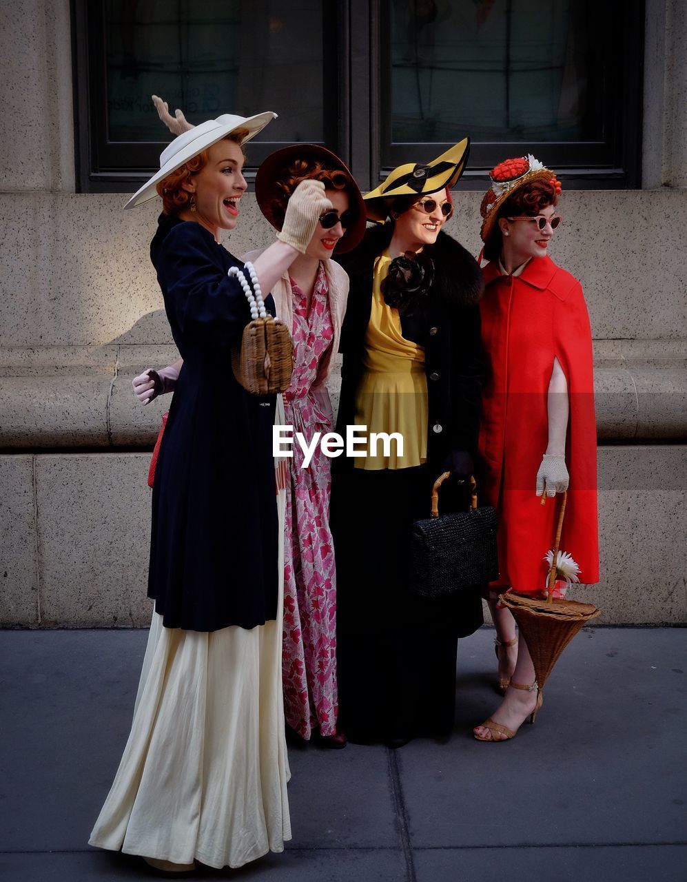 Female friends in old-fashioned clothes standing on sidewalk