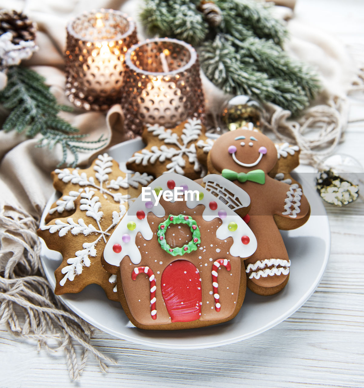 Christmas gingerbread in the plate and candles on white wooden background. top view.