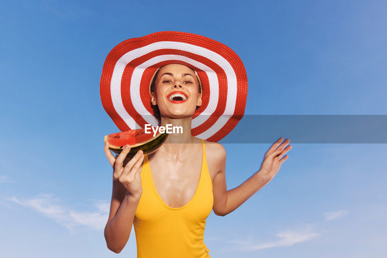portrait of young woman wearing hat against blue sky