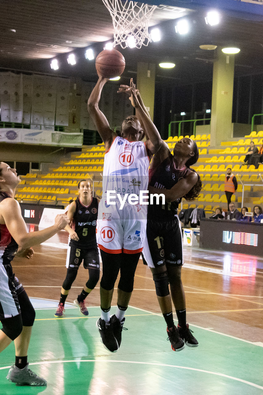 GROUP OF PEOPLE PLAYING BASKETBALL IN COURT