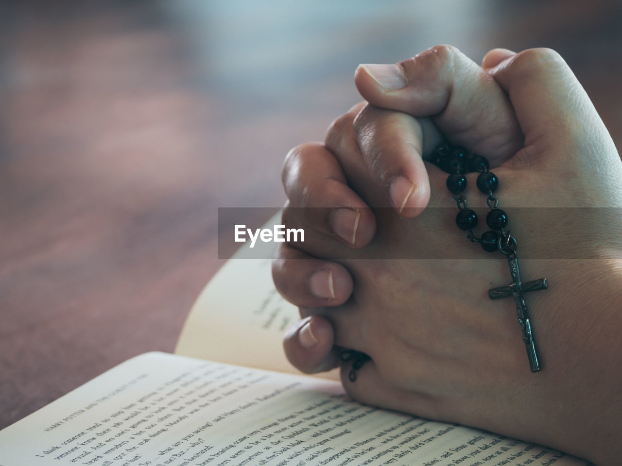 Cropped image of person with hands clasped on book