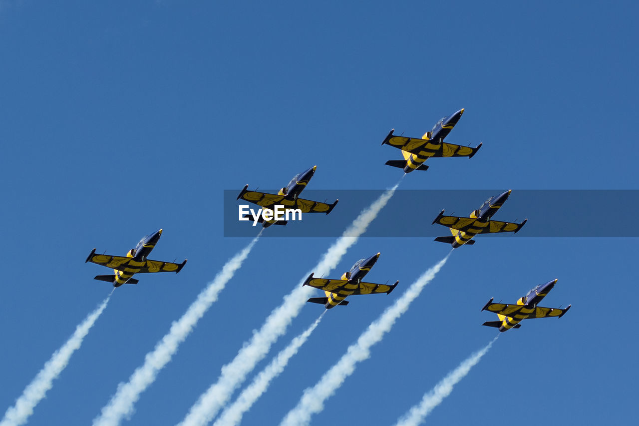 Low angle view of airshow against clear blue sky