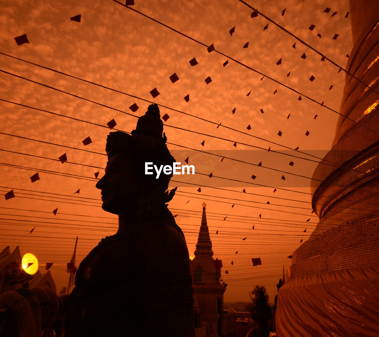 Buddha statue at temple against sky during sunset