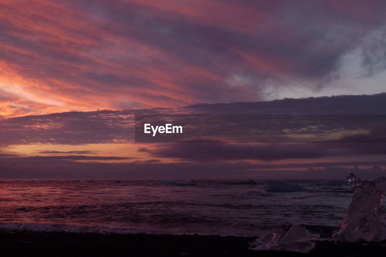 SCENIC VIEW OF SEA AGAINST DRAMATIC SKY DURING SUNSET