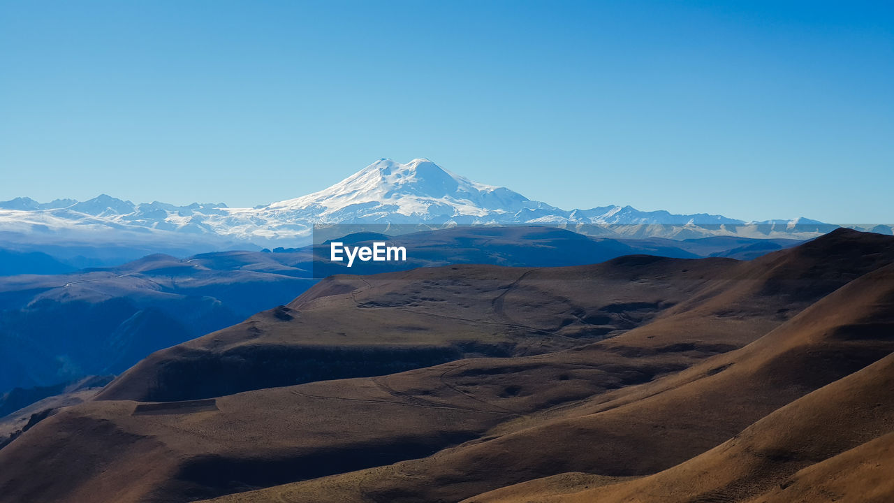 Scenic view of snowcapped mountains against clear blue sky