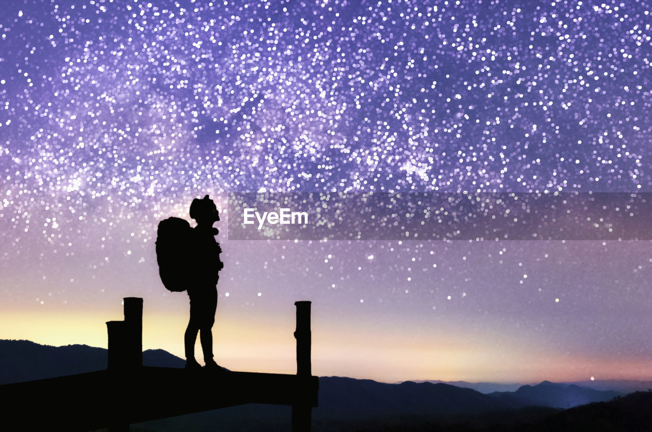 Milky way. night sky with stars and silhouette of a standing happy women on the mountain, 