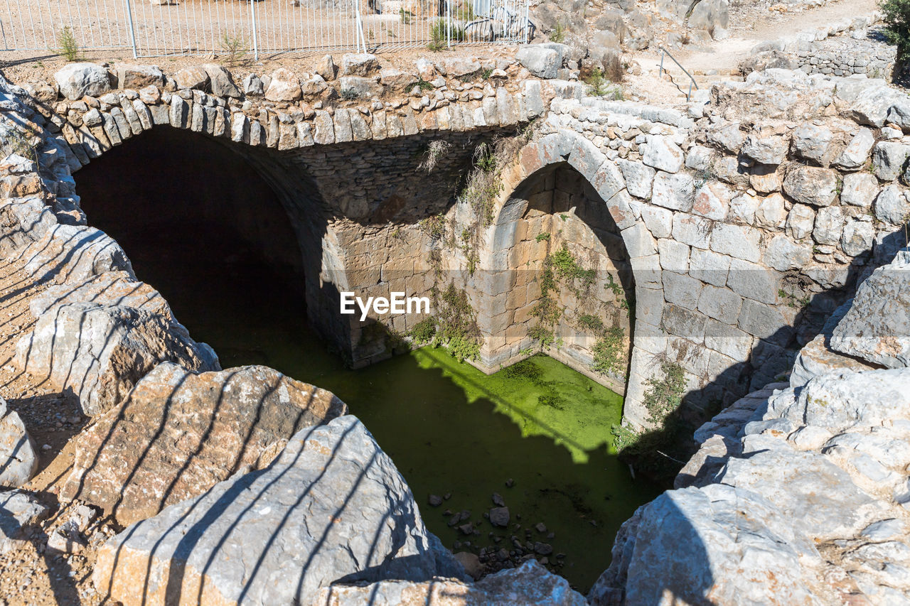 ARCH BRIDGE OVER RIVER AGAINST ROCKS