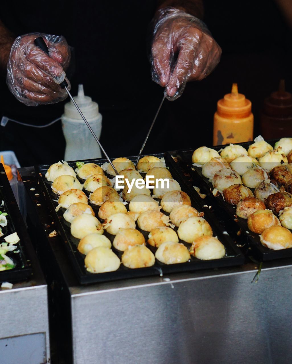 Midsection of man preparing takoyakis