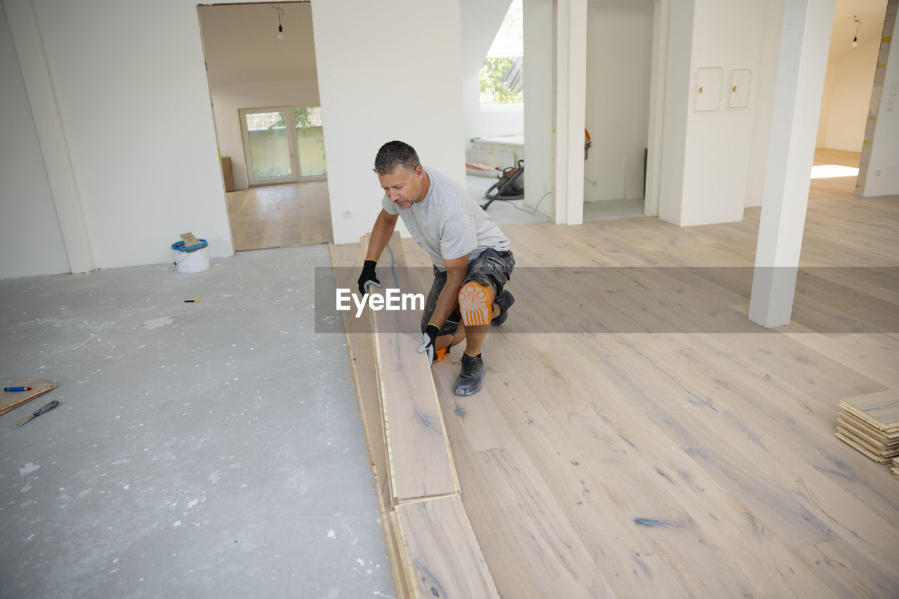 floor, flooring, indoors, men, child, childhood, wood flooring, hardwood, laminate flooring, lifestyles, home interior, full length, one person, wood, domestic life, adult, room, domestic room, hardwood floor, casual clothing, leisure activity, house, copy space, looking, person, holding, sitting, day