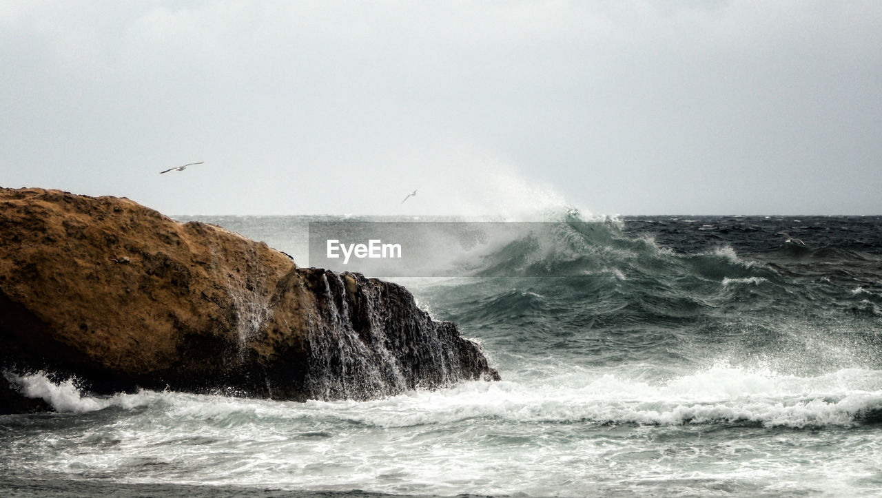 Waves splashing on sea against sky