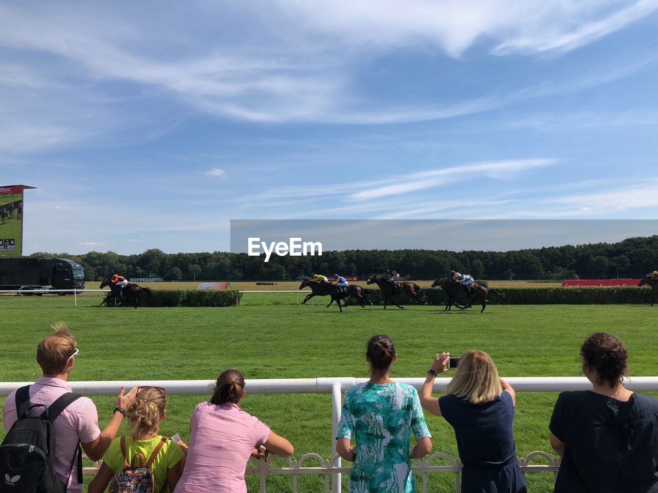 People watching horse racing against sky