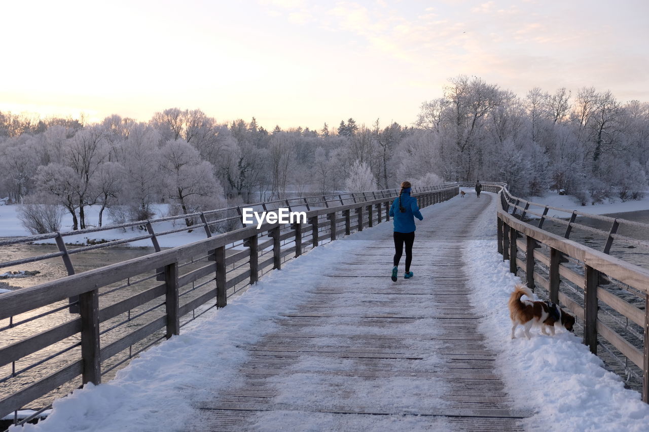 REAR VIEW OF PERSON ON SNOW COVERED LANDSCAPE