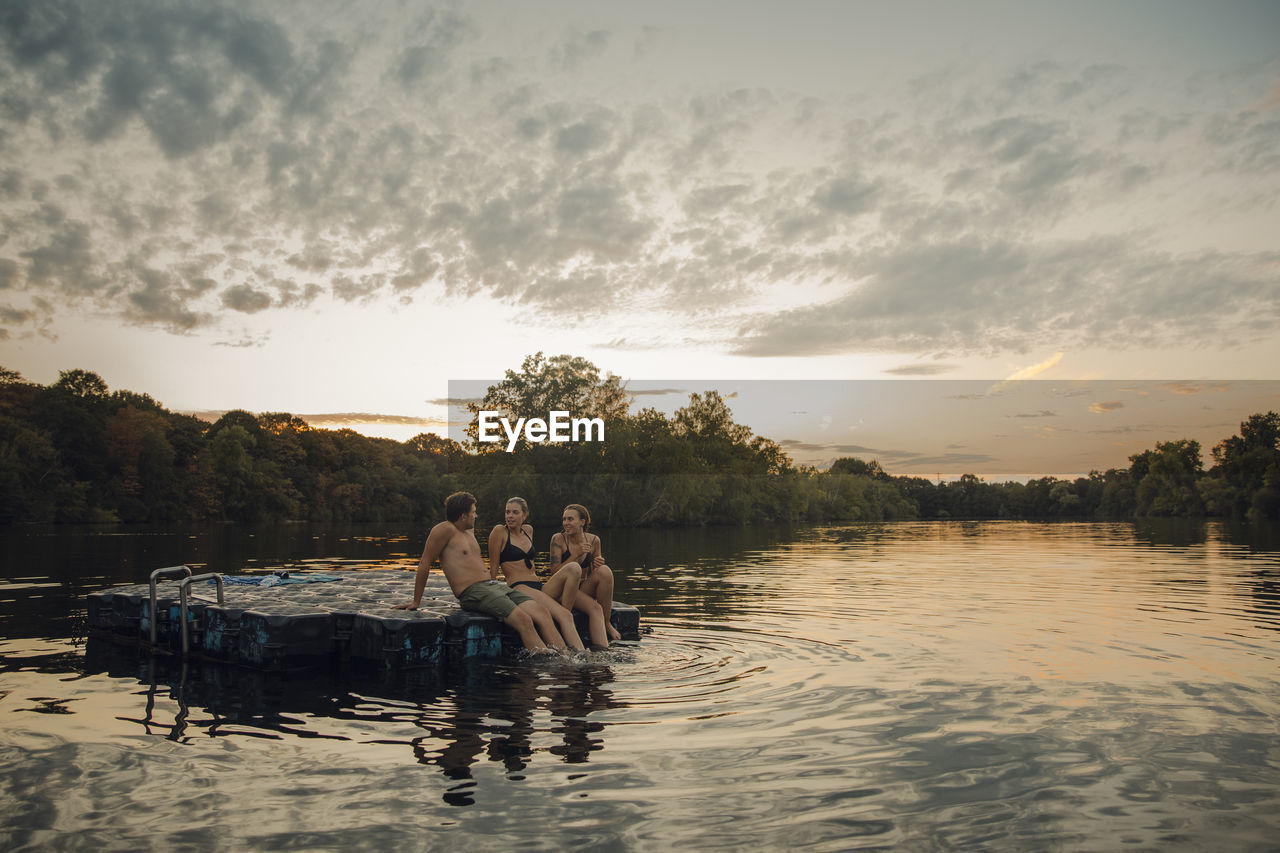 Friends having fun at the lake, sitting on bathing platform