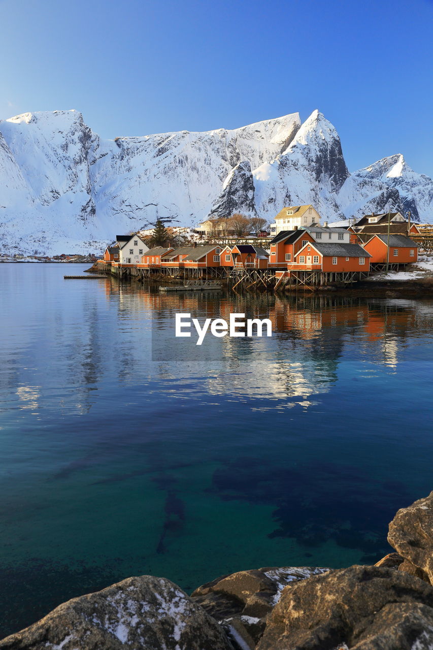 Stilt houses by lake against snowcapped mountains