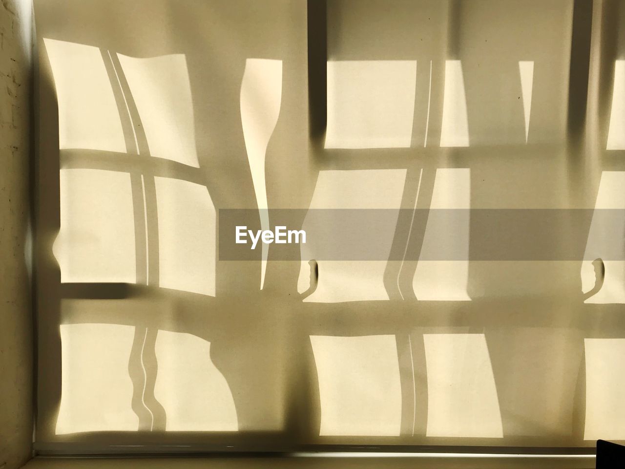 A window shadow on beige curtains in sunlight