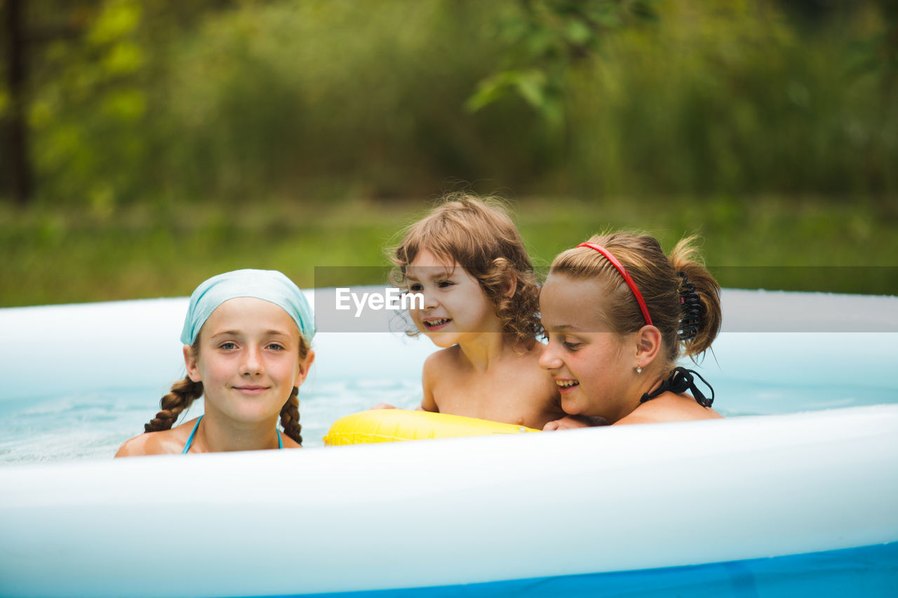 Mother with daughters relaxing in wading pool