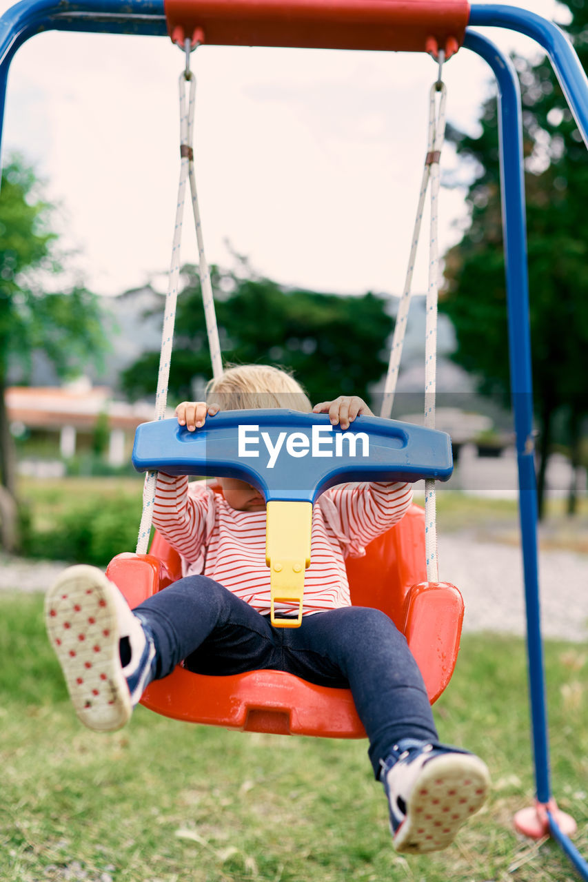 REAR VIEW OF CHILDREN ON SWING