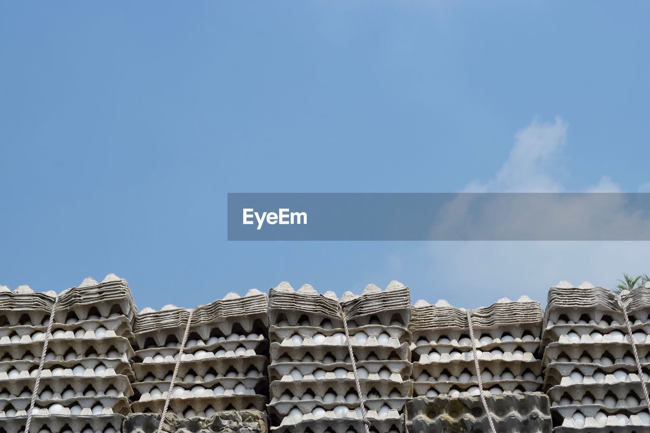 Low angle view of egg in stacked cartons against sky